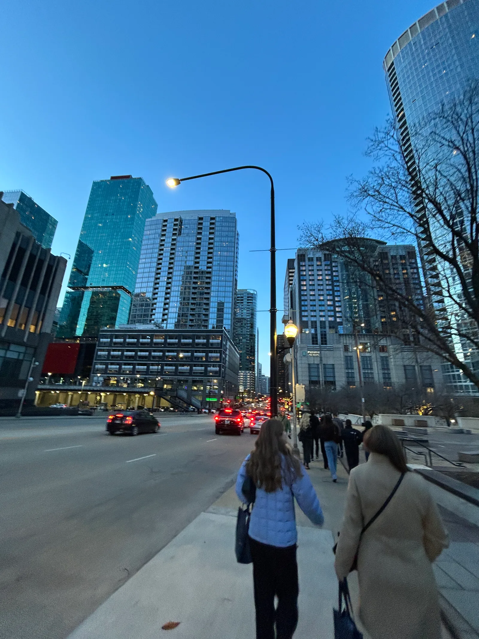 People walking along a Chicago street between downtown buildings.